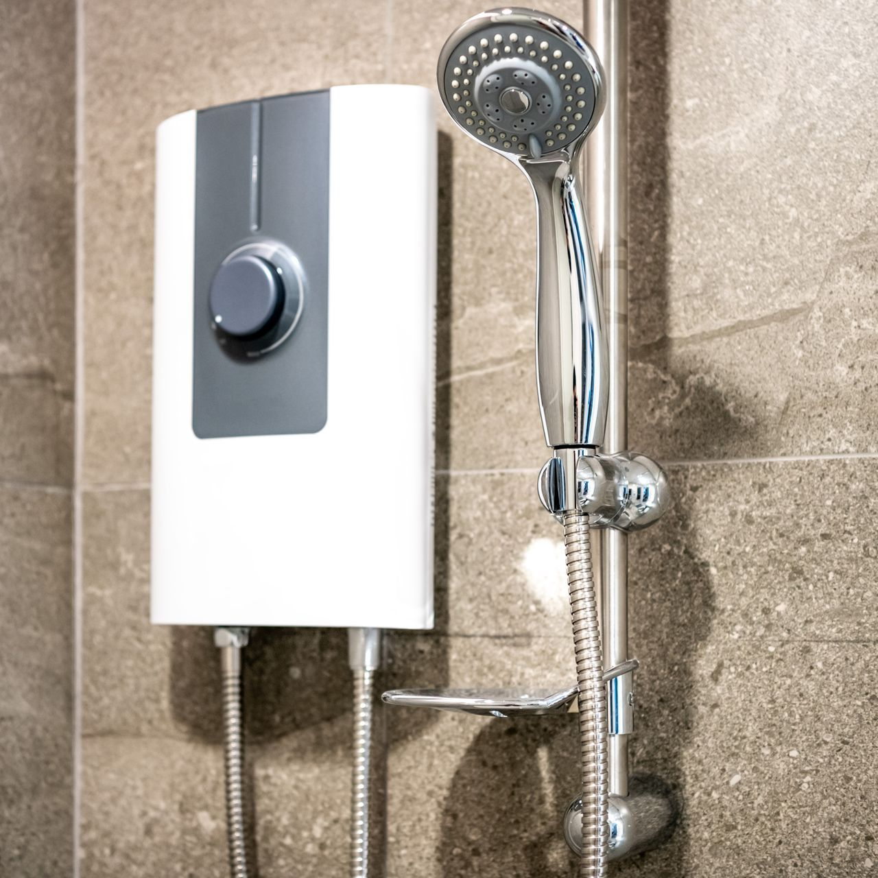 Electric shower and shower head on a gray tile wall.