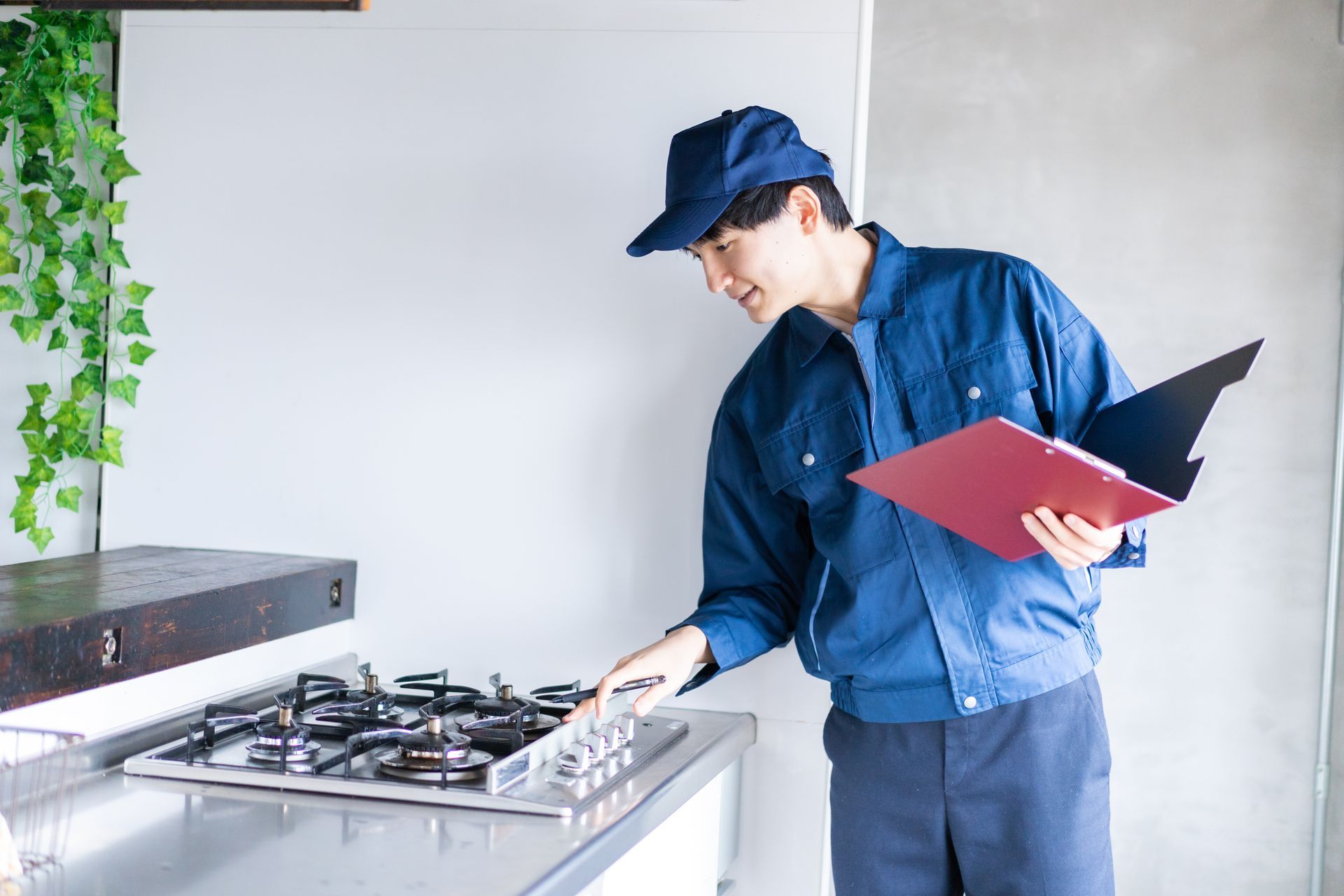 a man is standing in a kitchen looking at a stove while holding a clipboard .