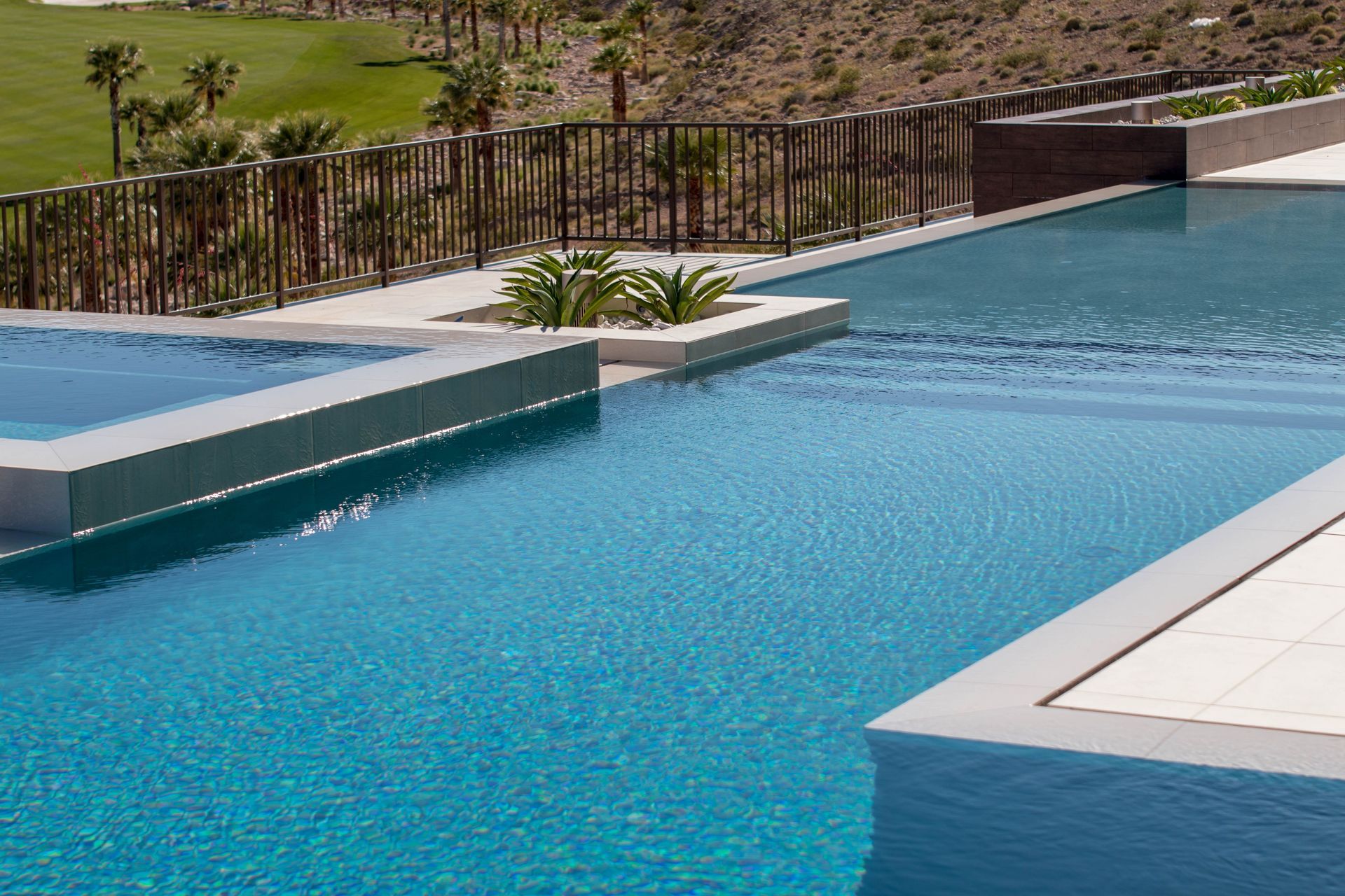 A large swimming pool with a fence around it and a golf course in the background.