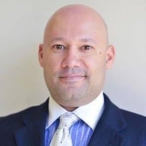 A man and a woman are sitting on a dock overlooking a lake.