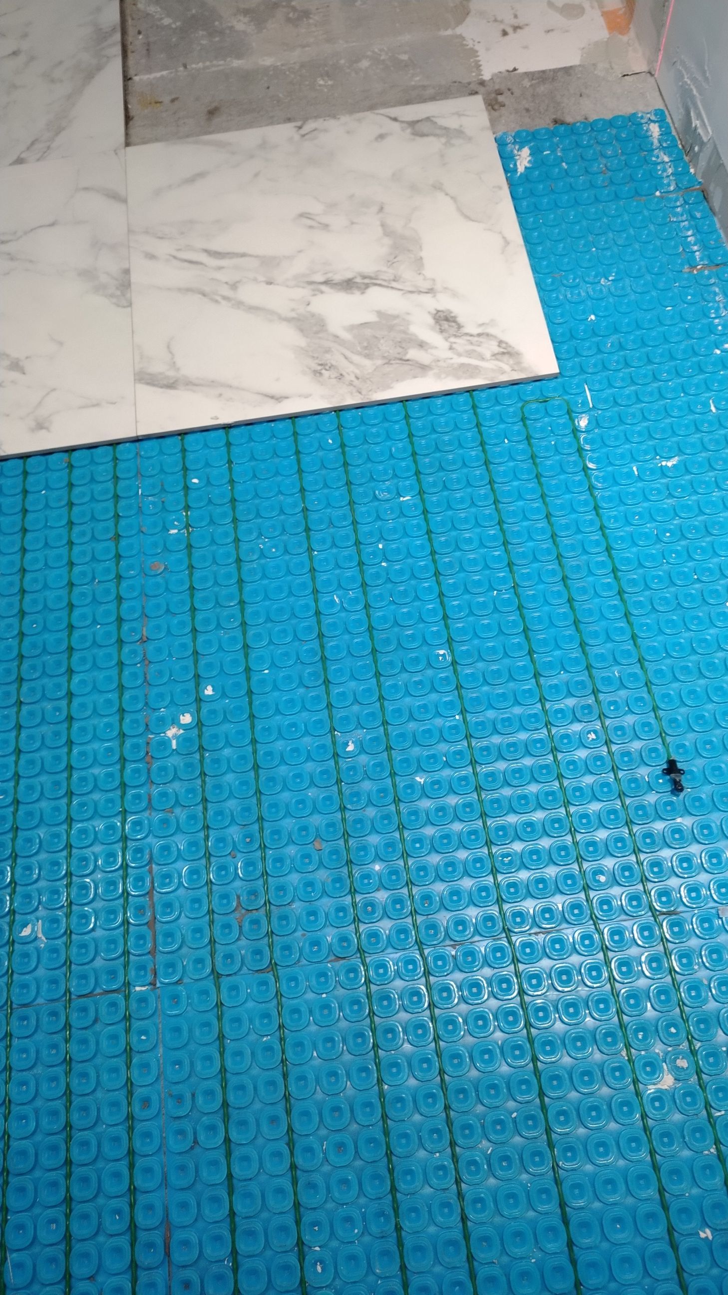 Membrane de sol bleue avec carrelage partiellement posé, scène de construction.