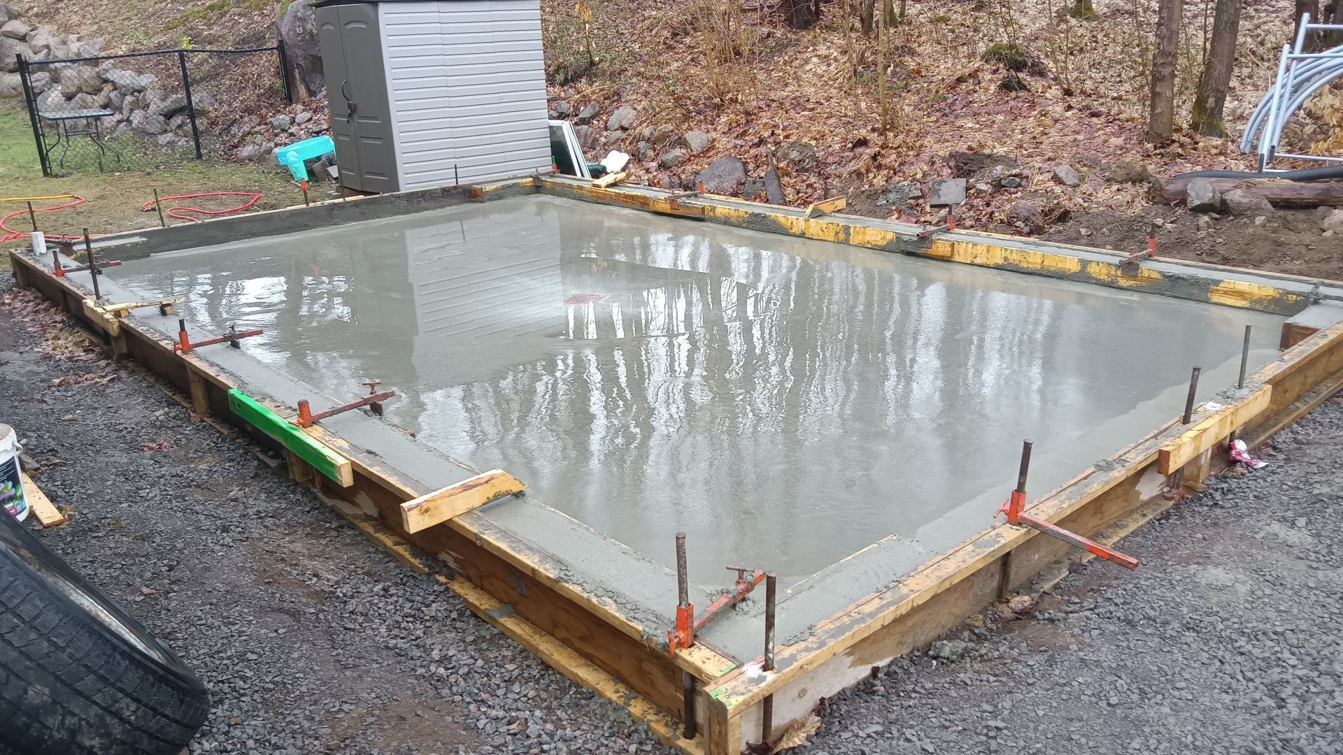 Dalle de béton fraîchement coulée dans un cadre en bois, à l'extérieur.