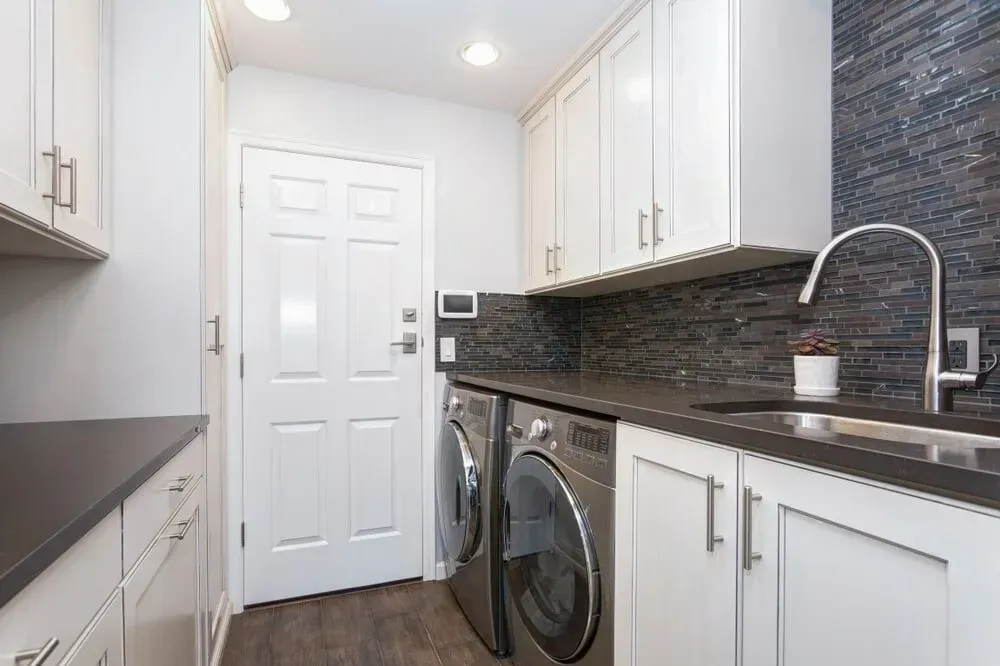 A Black Countertop And A Stainless Steel Sink With Laundries — Pioneer Cabinets in Paget, QLD
