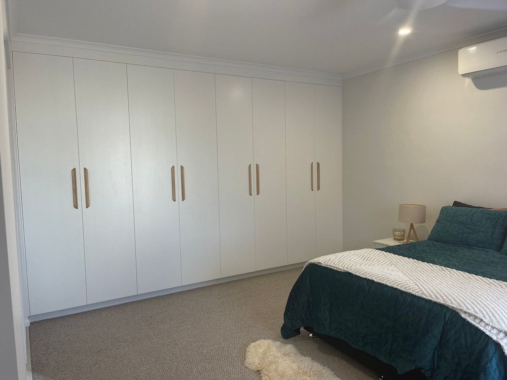 A Bedroom With A Bed, Closets And A Dog — Pioneer Cabinets in Rural View, QLD