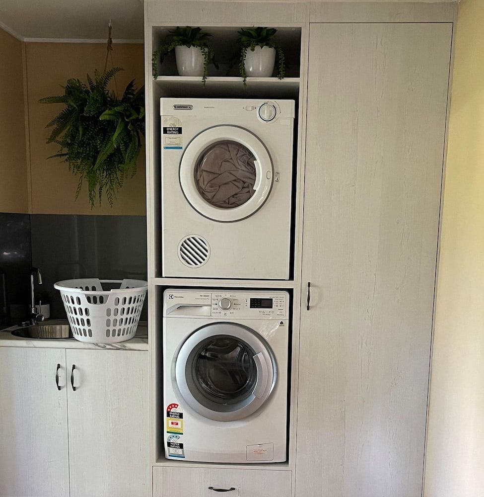 A Washer And Dryer Are Stacked On Top Of Each Other In A Laundry Room — Pioneer Cabinets in Paget, QLD