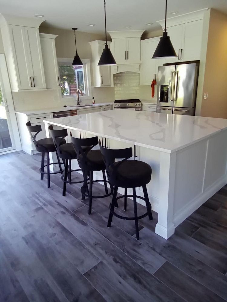 A Kitchen With A Large Island And Stools — Pioneer Cabinets in Paget, QLD