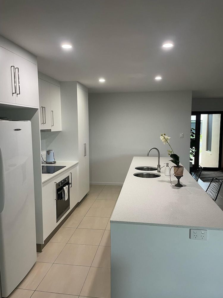 A Kitchen With White Cabinets And A Large Island — Pioneer Cabinets in Paget, QLD