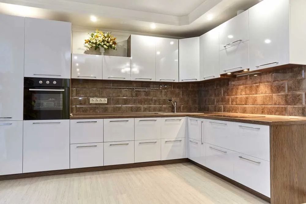 A Kitchen With White Cabinets And A Black Oven — Pioneer Cabinets in Paget, QLD
