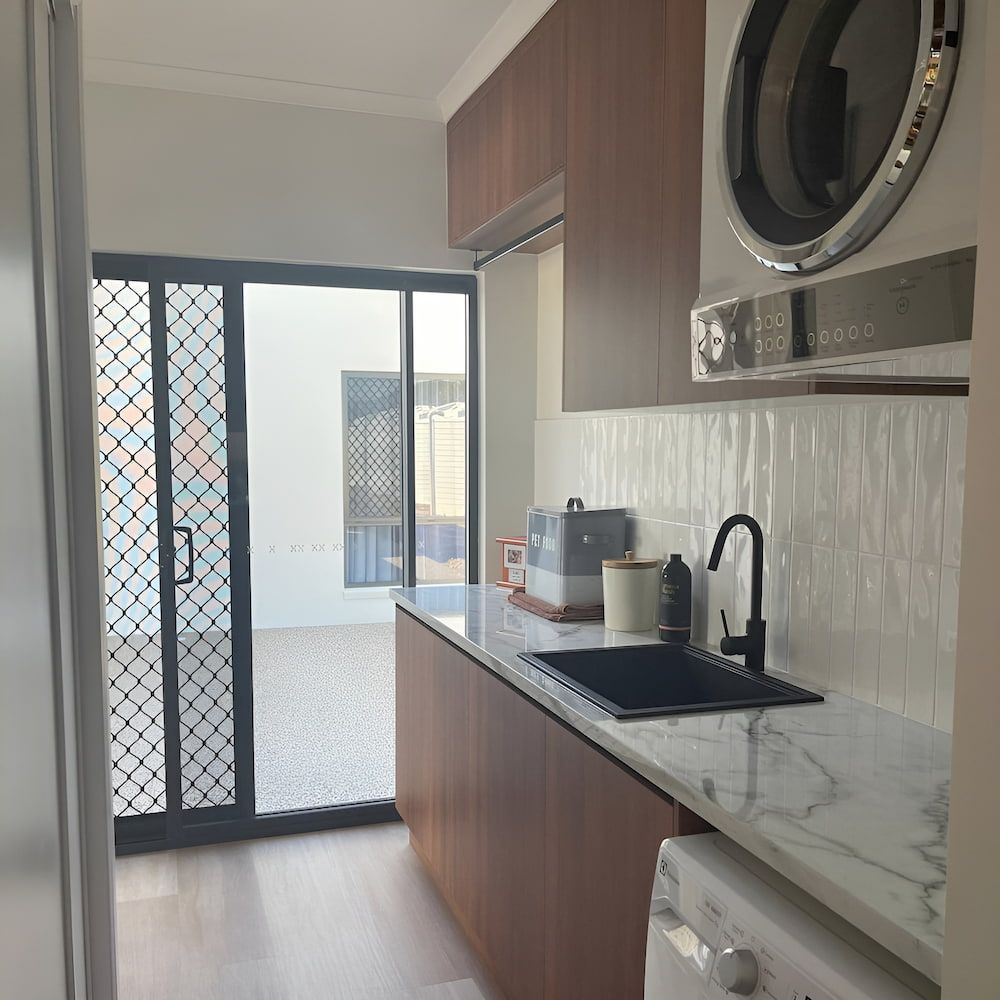 A Kitchen With A Sink And A Washer And Dryer — Pioneer Cabinets in Airlie Beach, QLD