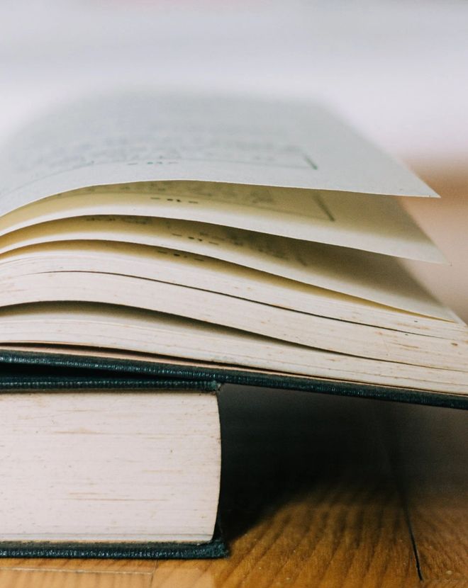 An open book is sitting on a wooden table.