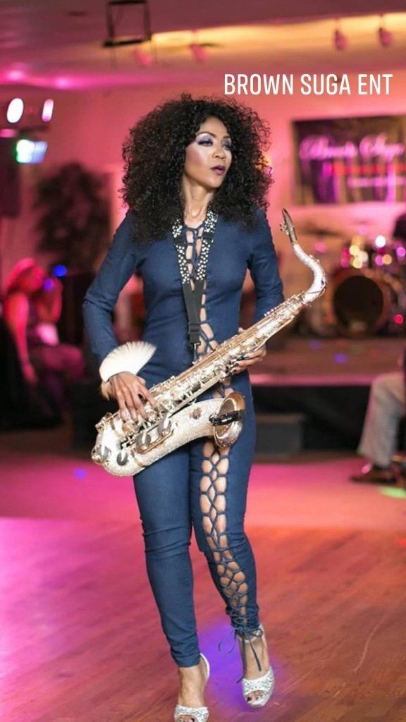A woman is playing a saxophone on a stage.