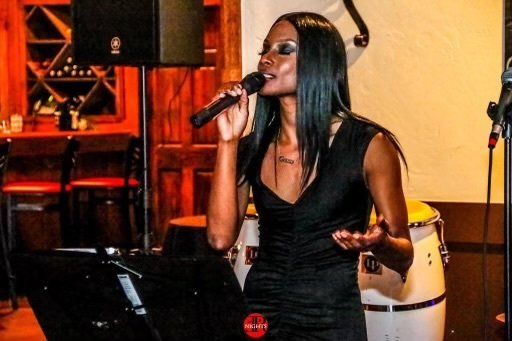 A woman in a black dress is singing into a microphone