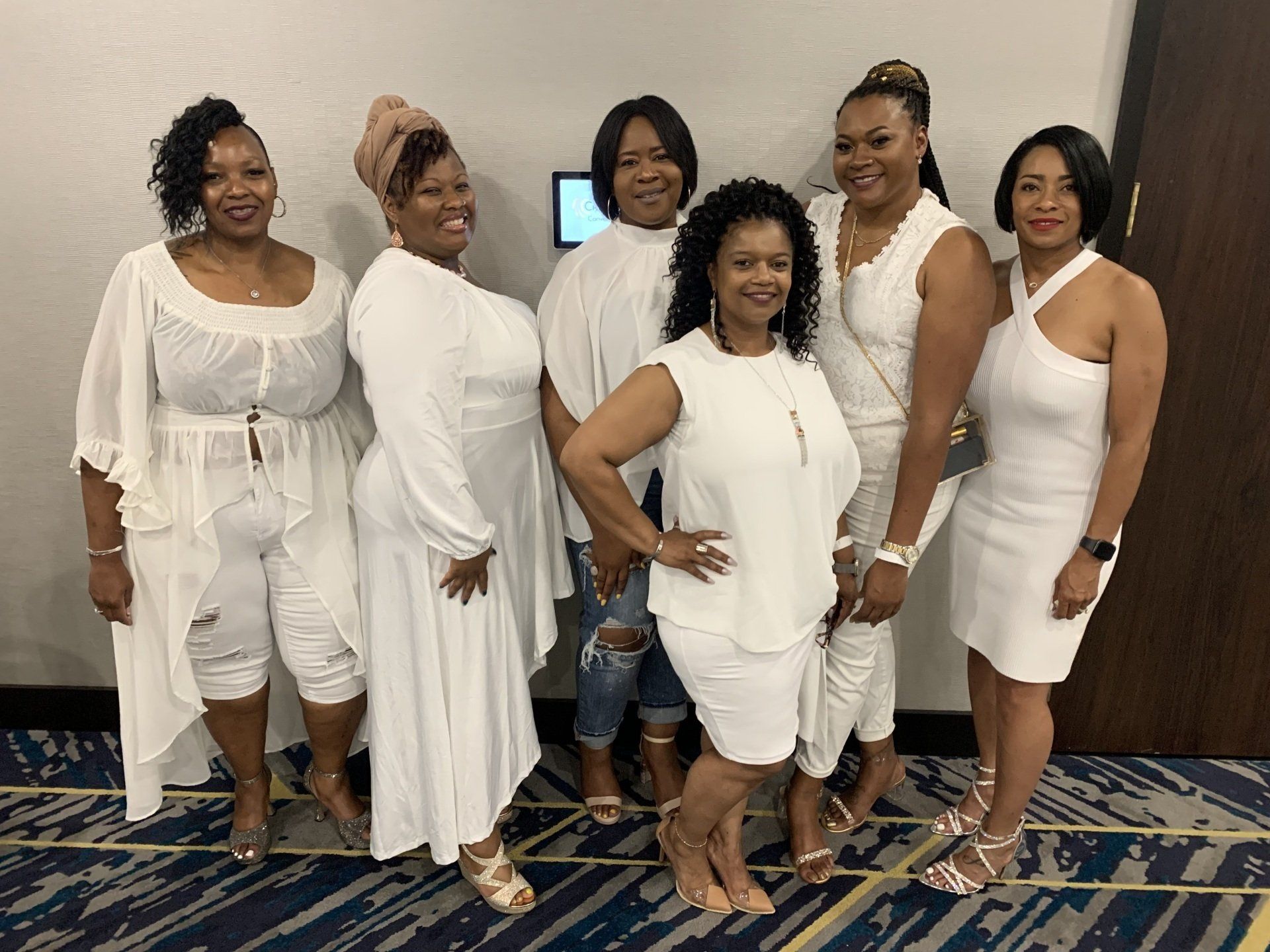A group of women in white dresses are posing for a picture.