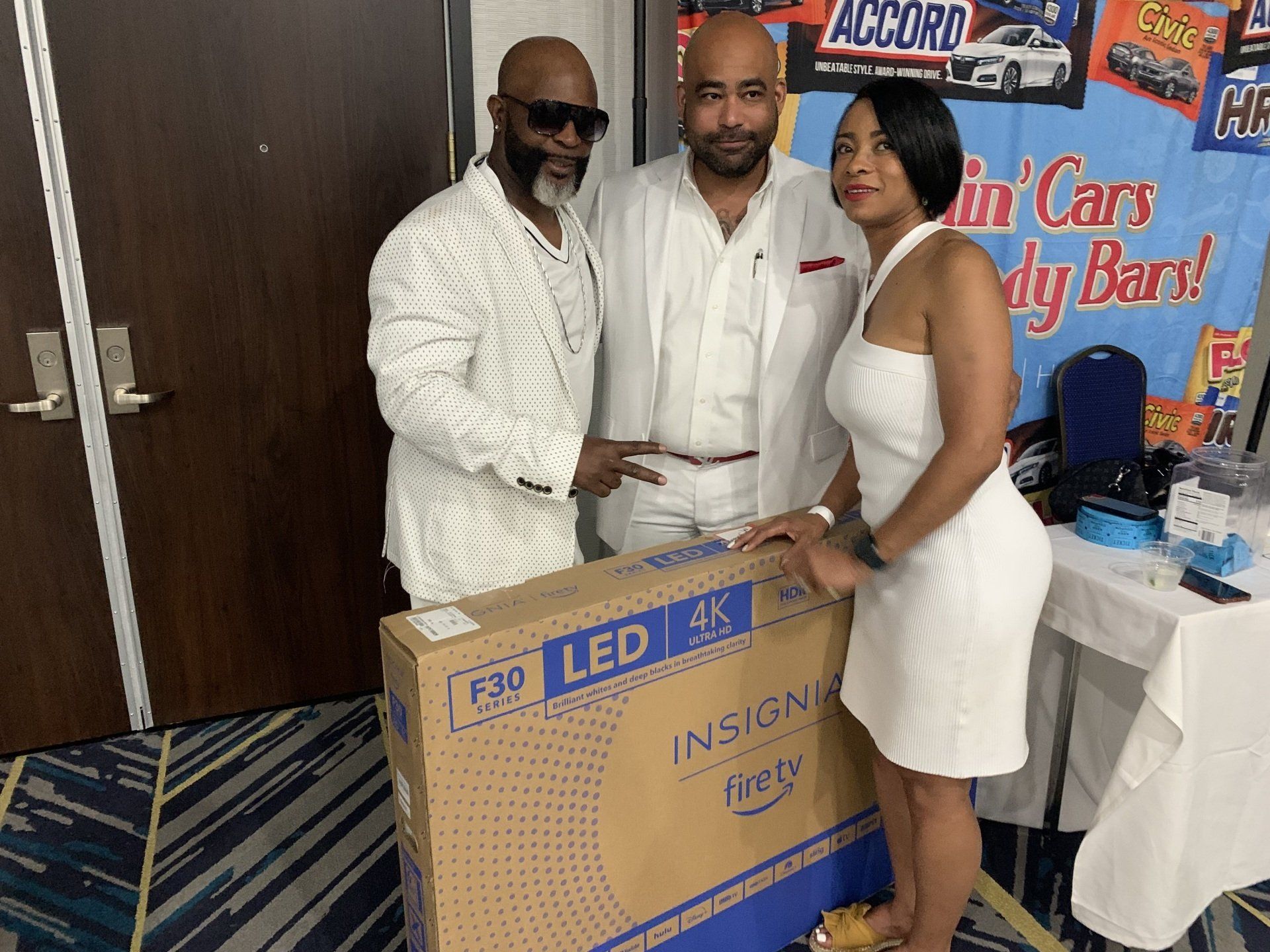 A man and two women are standing next to a box that says led 4k on it.