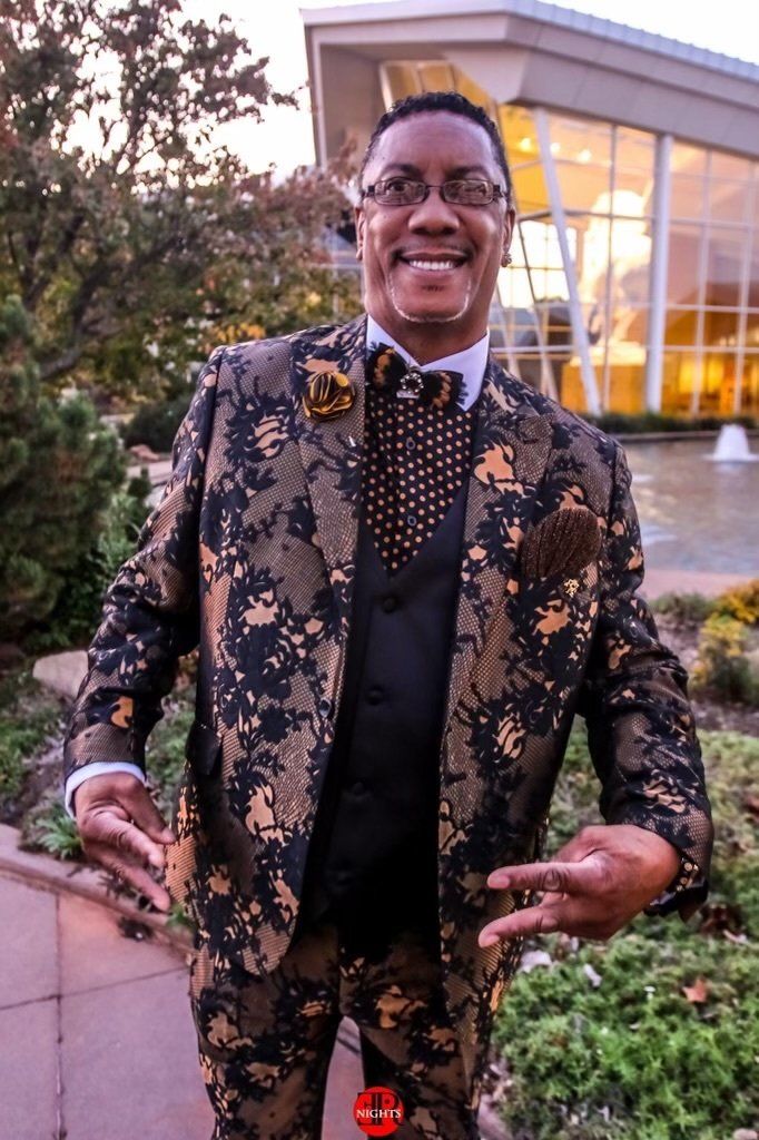 A man in a suit and tie is standing in front of a building