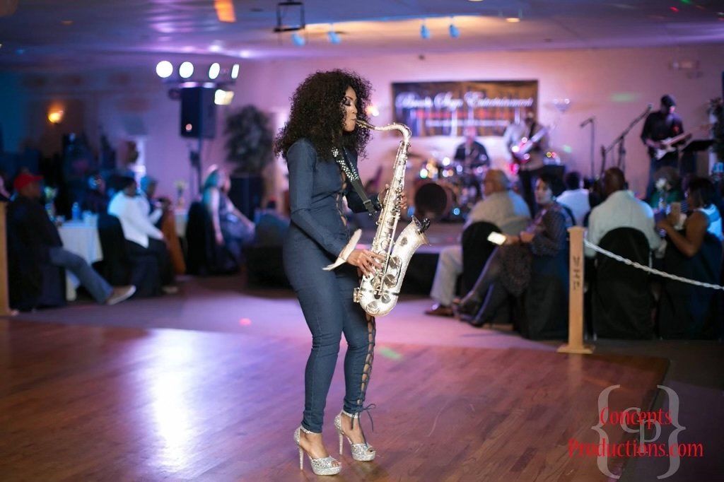 A woman is playing a saxophone on a dance floor.
