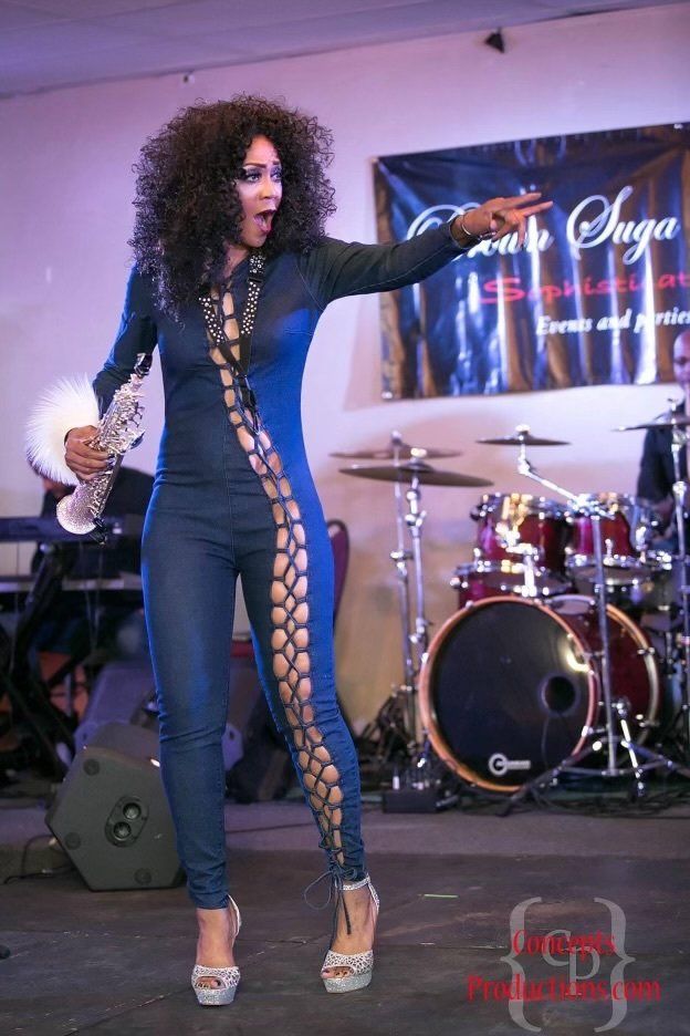 A woman in a blue jumpsuit is standing in front of a drum set