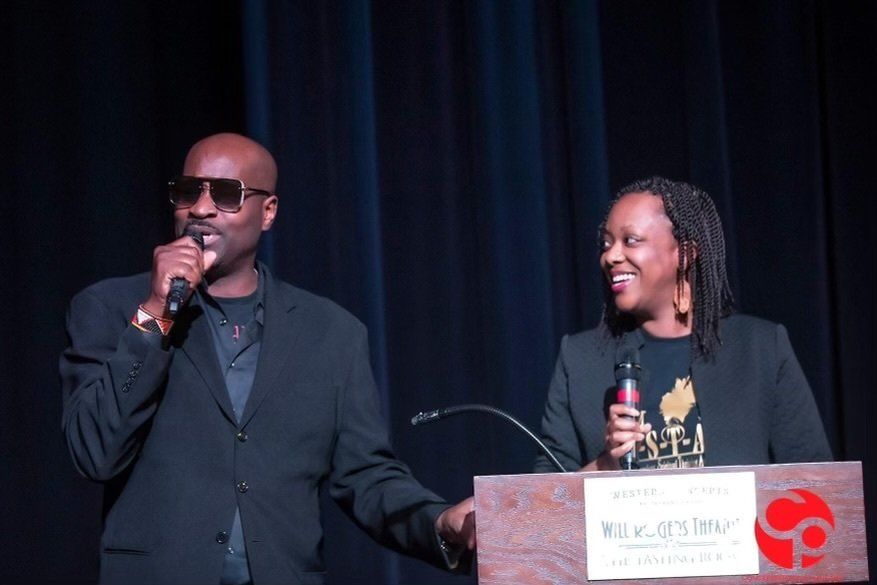 A man is holding a microphone while standing next to a woman at a podium.
