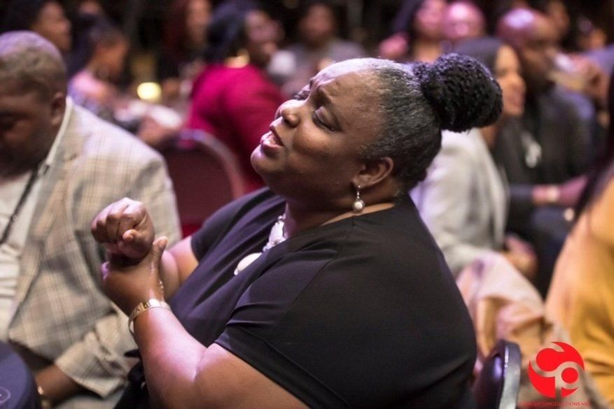 A woman in a black shirt is sitting in a crowd of people.