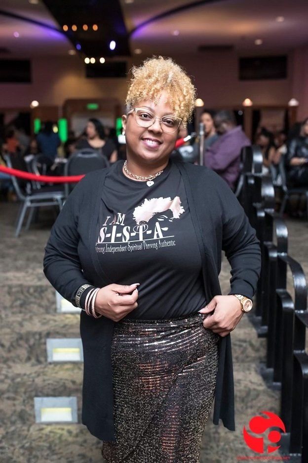 A woman wearing a black shirt and a gold skirt is standing in a room.