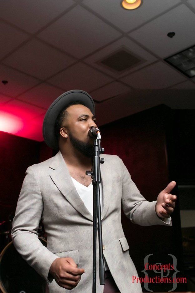 A man in a suit and hat is singing into a microphone.