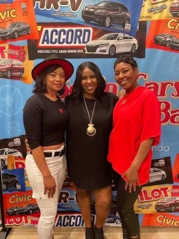 Three women are posing for a picture in front of a sign that says accord.