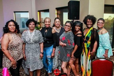 A group of women are posing for a picture together in a room.