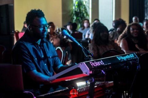 A man is playing a keyboard in front of a crowd.