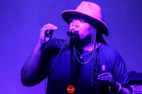 A man in a hat is singing into a microphone.