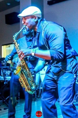 A man in a white hat is playing a saxophone on stage