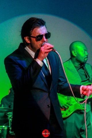 A man in a suit is singing into a microphone