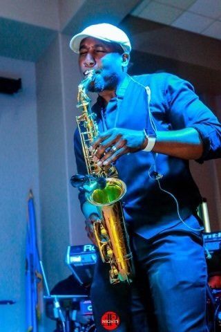 A man in a white hat is playing a saxophone