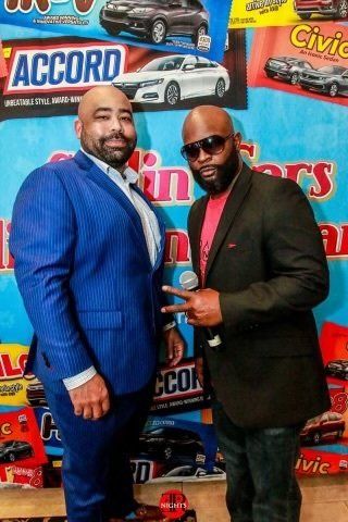 Two men are standing next to each other in front of a sign that says accord