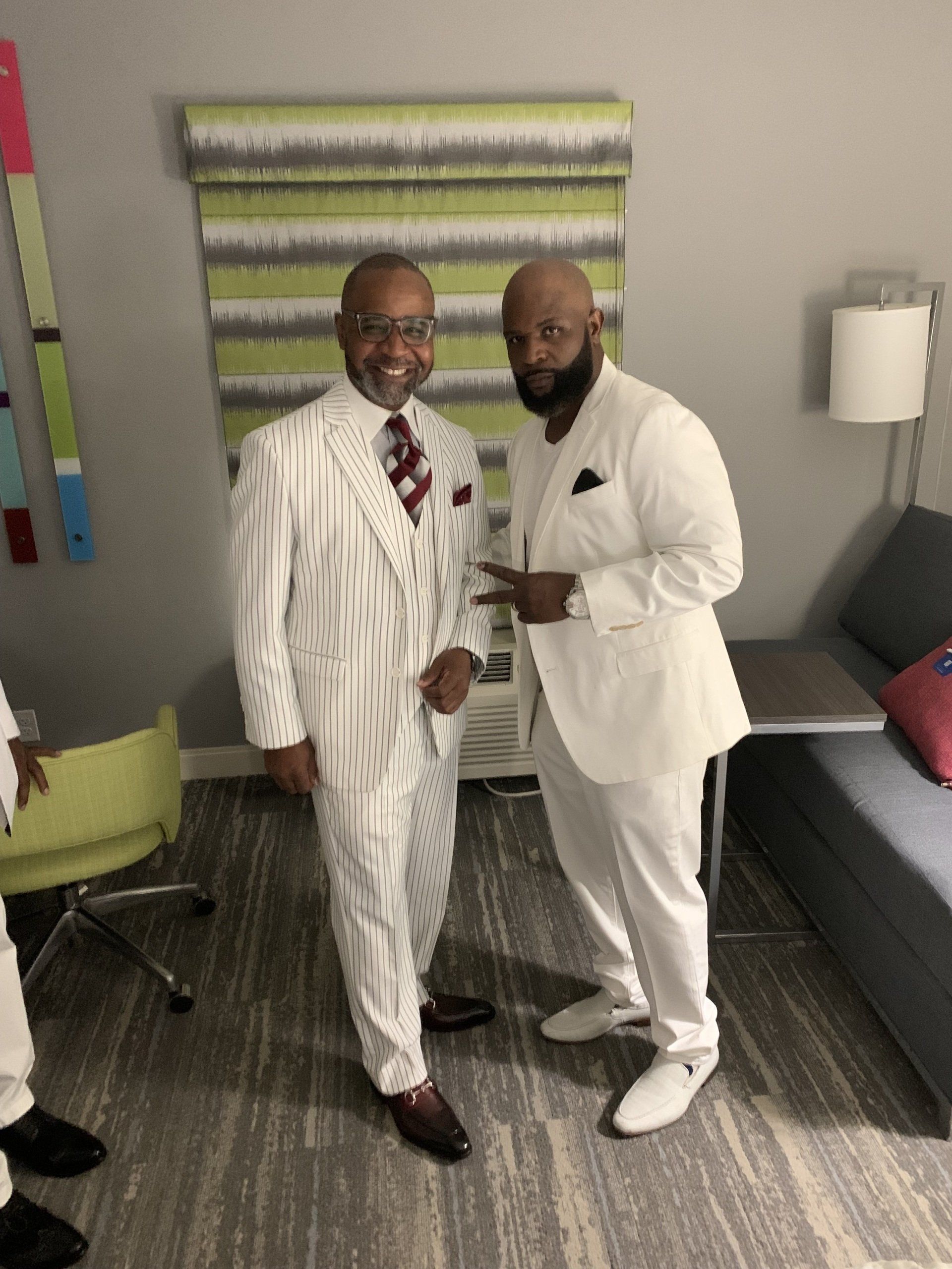 Two men in white suits are standing next to each other in a room.
