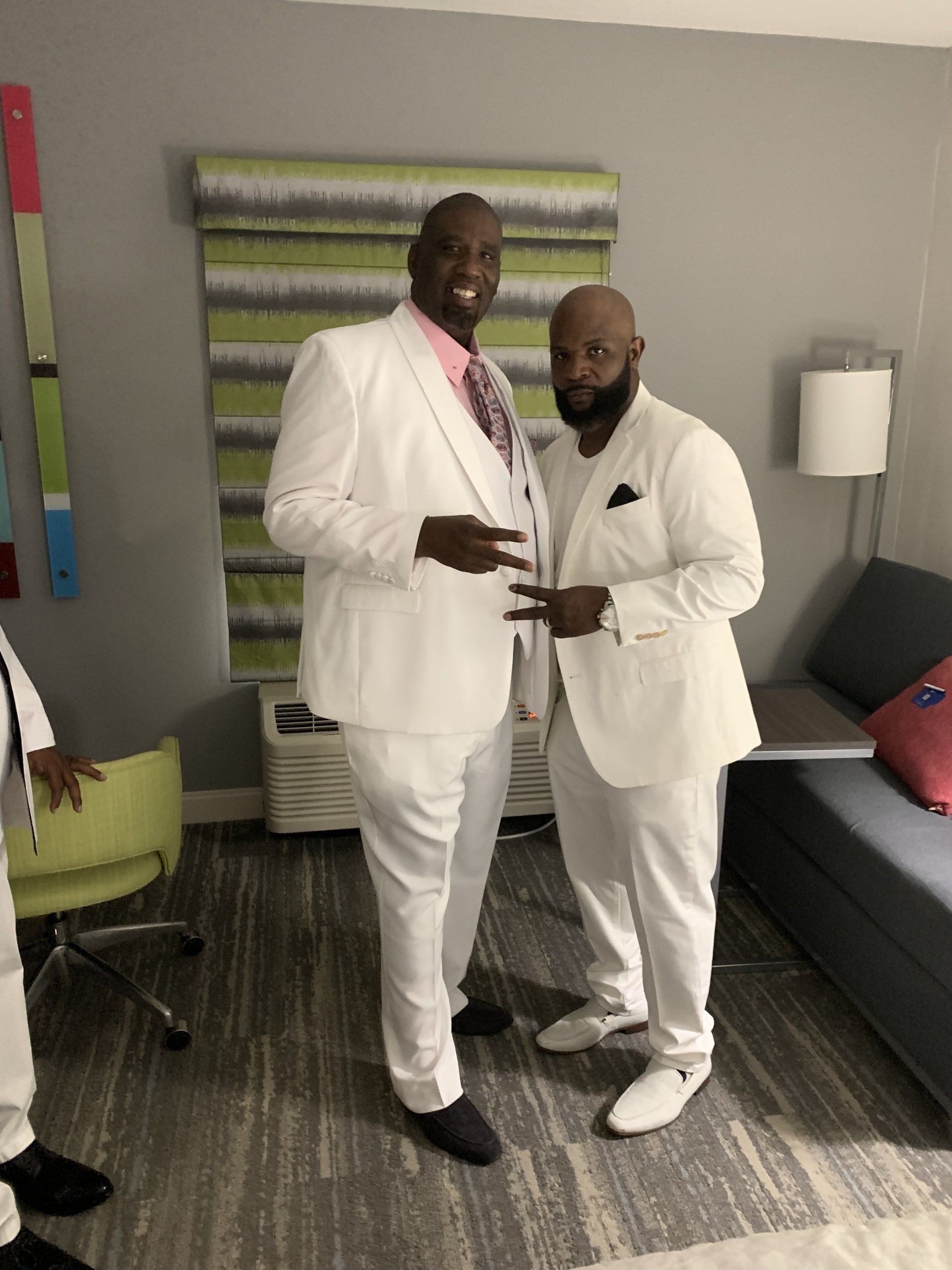 Two men in white suits are standing next to each other in a room.