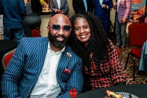 A man and a woman are posing for a picture while sitting at a table.