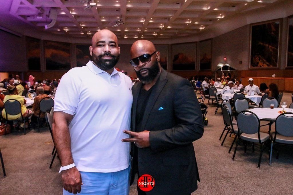 Two men are posing for a picture in a large room.