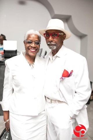 A man and a woman are posing for a picture while wearing all white