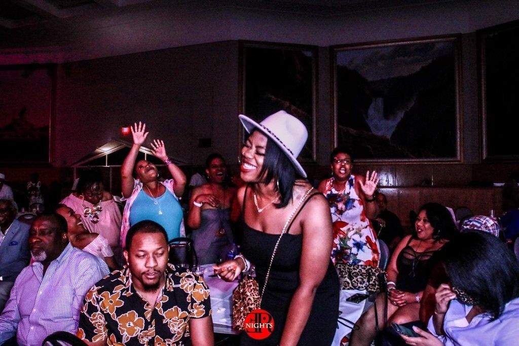 A woman in a hat is dancing in a crowd of people at a party.