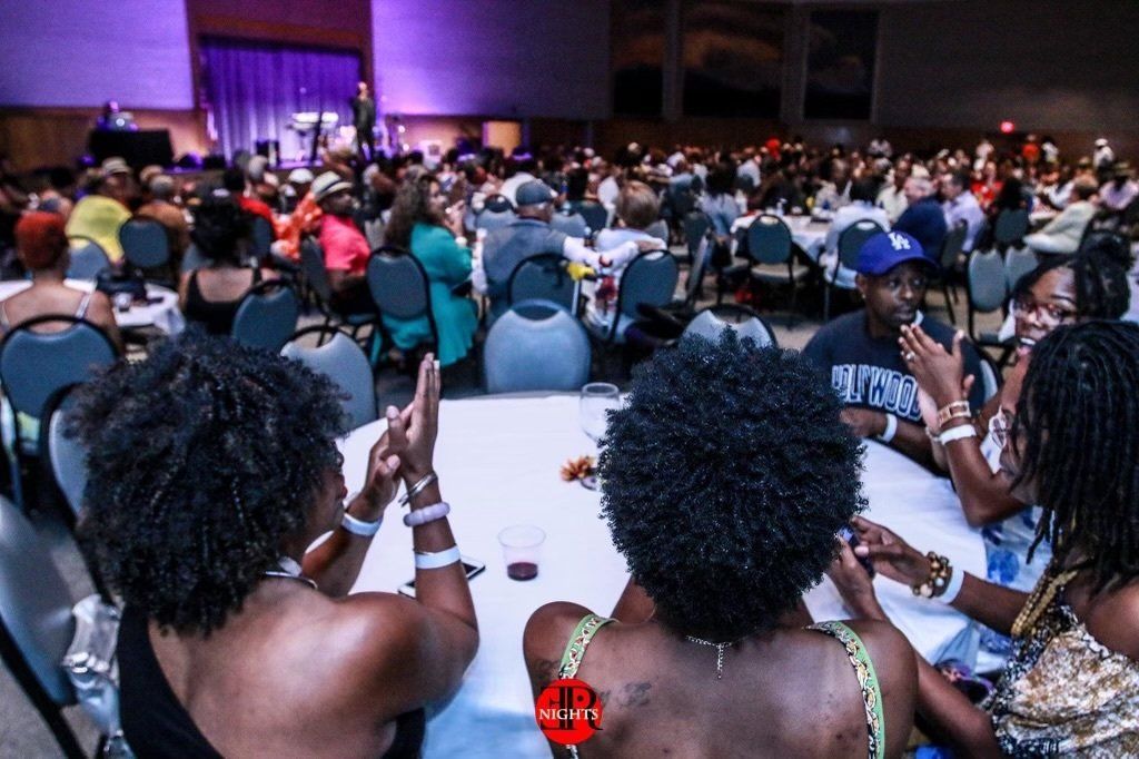 A group of people are sitting at tables in a large room.