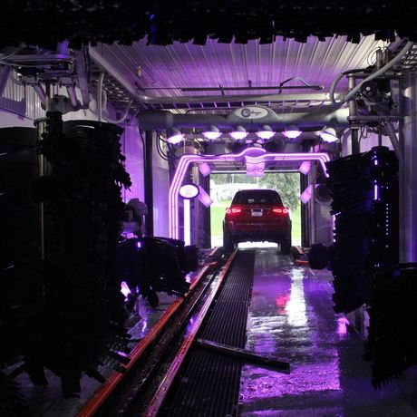 Hydro-Spray Tunnel Car Wash System. Blue car receiving car wash in tunnel.