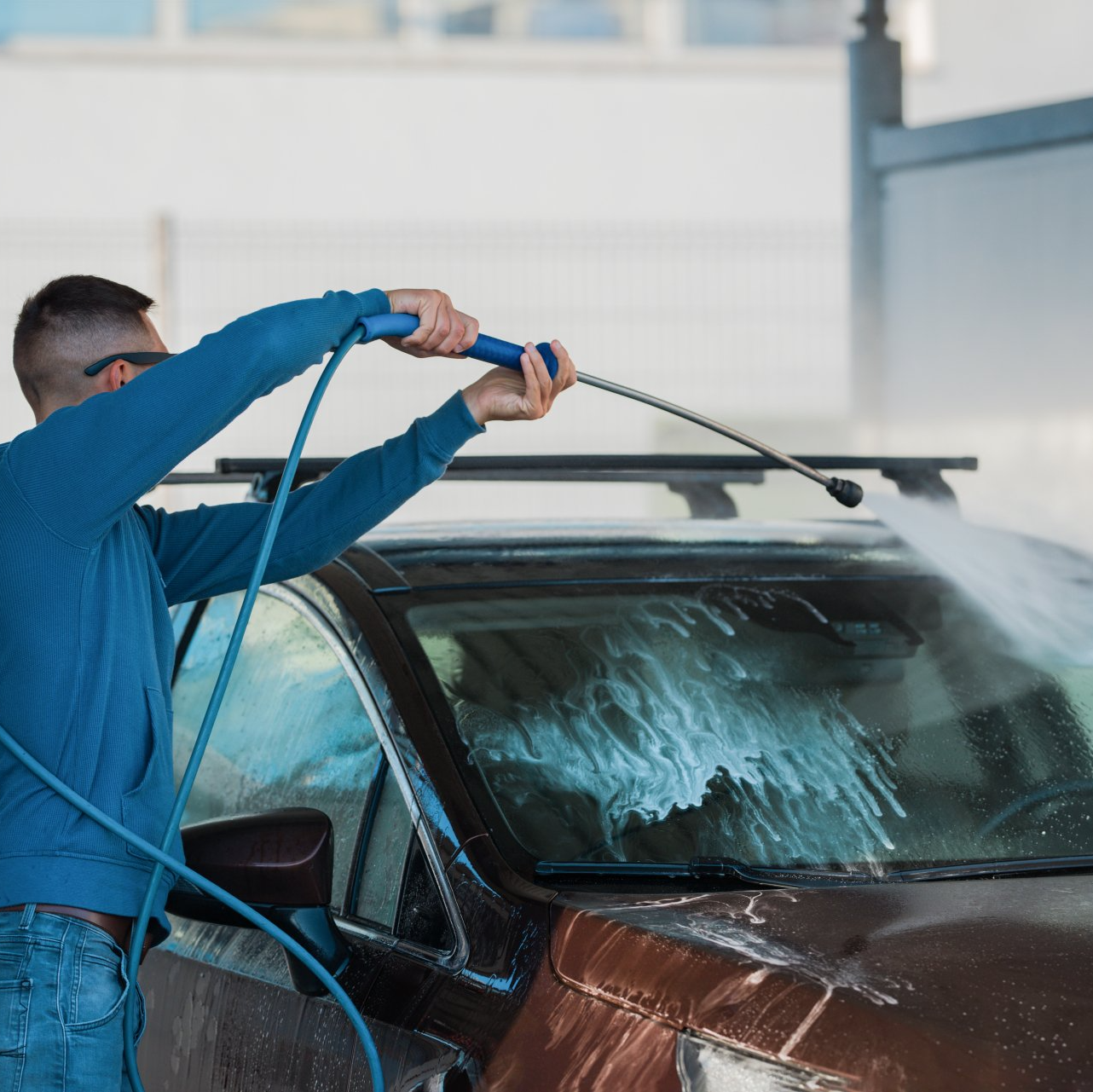 Man washing car with self serve pressure washer