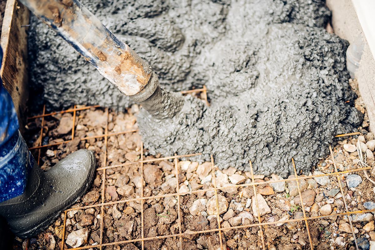 A person is pouring concrete into a hole in the ground.