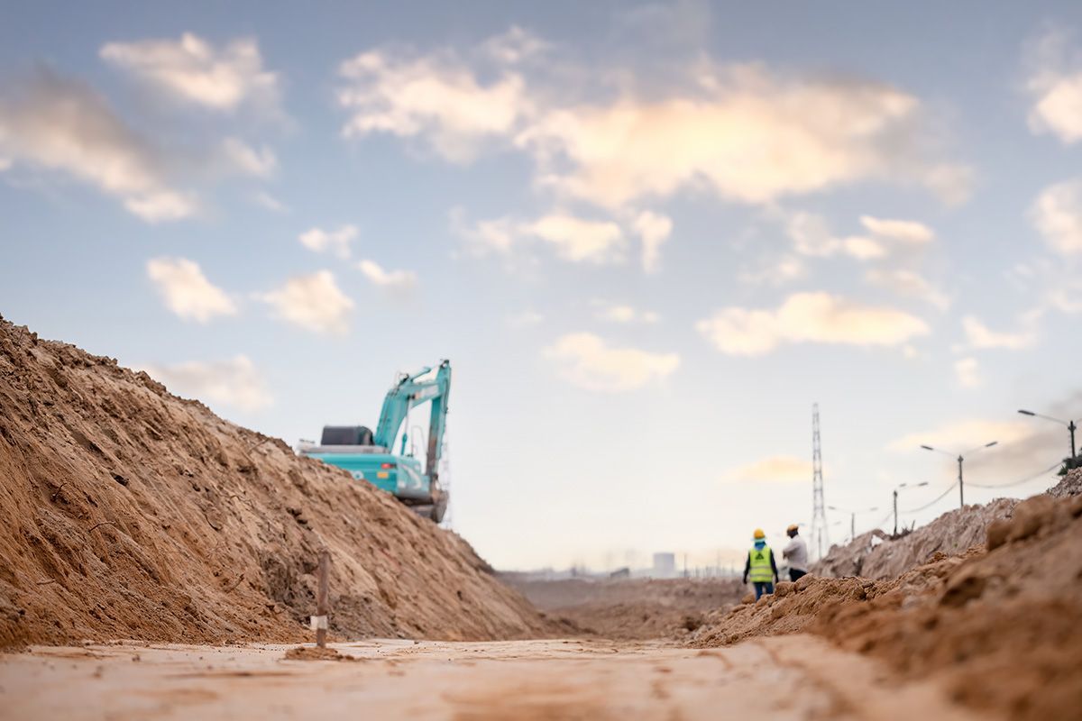 A construction site with a large pile of dirt and a bulldozer in the background.
