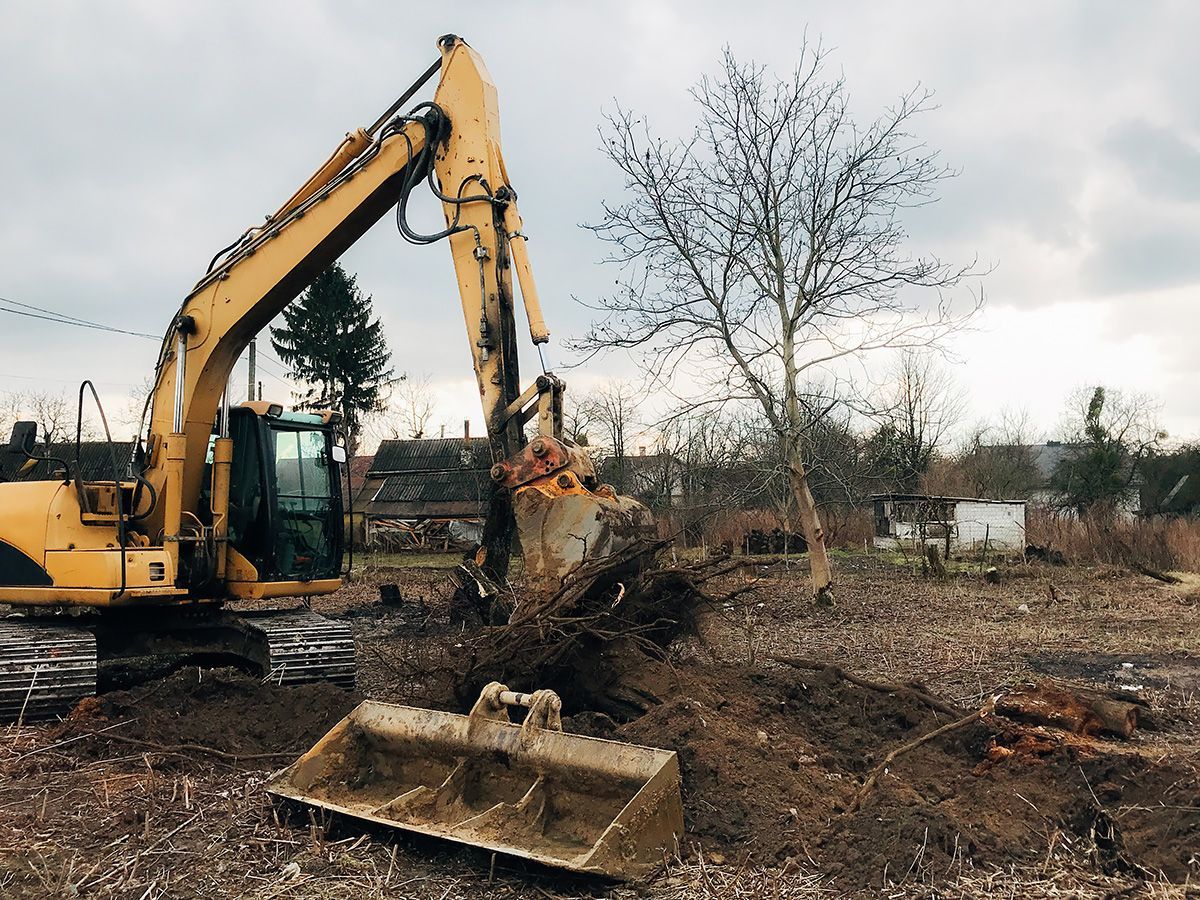 A yellow excavator is moving dirt in a field.