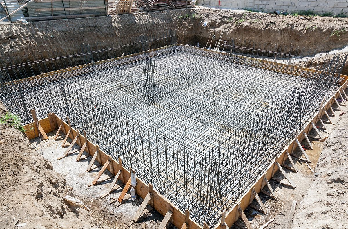 A concrete foundation is being built in a hole in the ground.