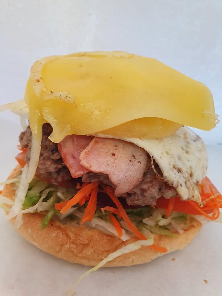 Burger with Melted Cheese, Fried Egg, Bacon and Shredded Vegetables — Mount Louisa Snack Bar in Mount Louisa, QLD