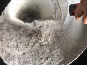 A person is cleaning a drain with a vacuum cleaner.