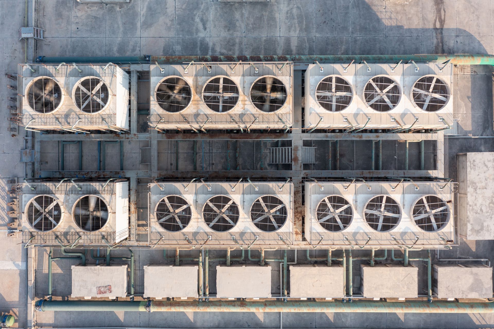 An aerial view of a row of air conditioners on the roof of a building.
