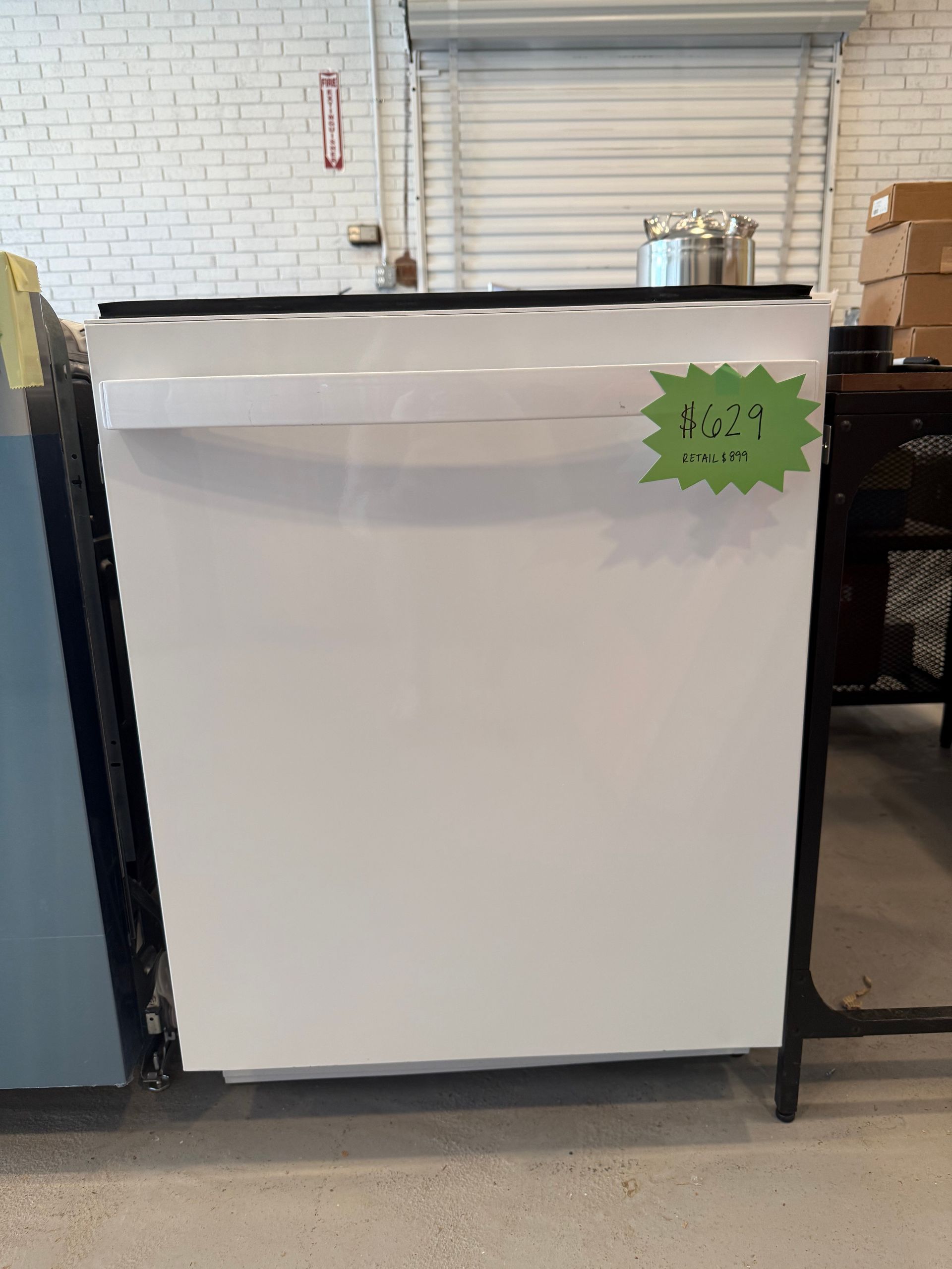 A white dishwasher with a green sticker on it is for sale in a store.